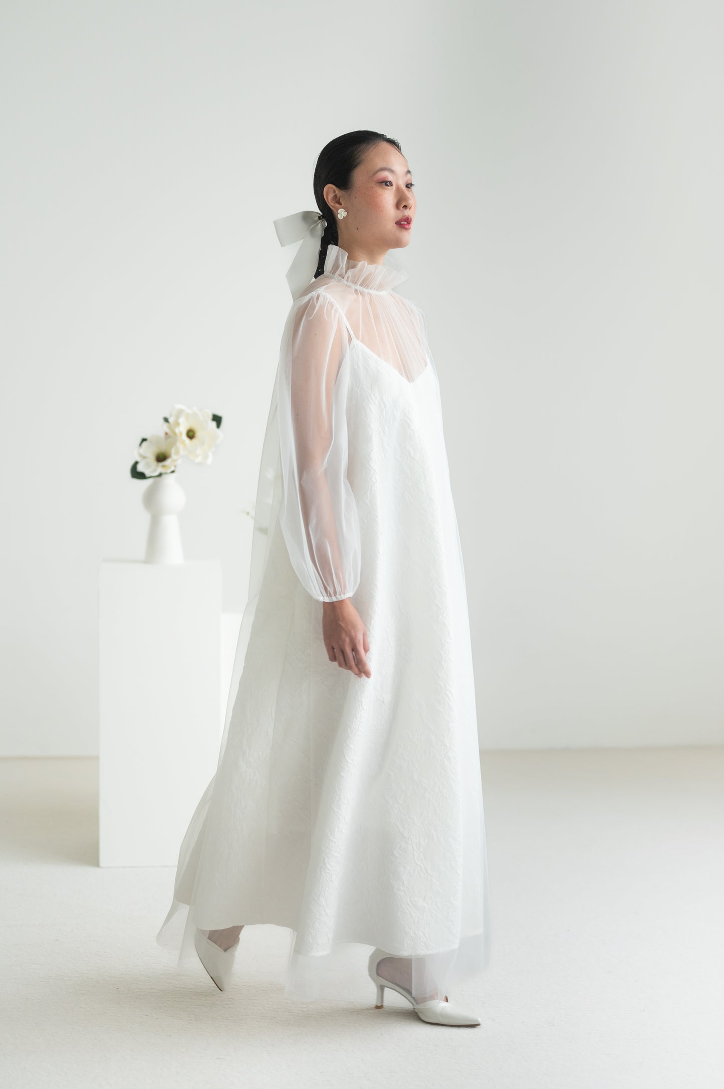 Sheer tulle dress with a high ruffled collar, puffed sleeves with elastic cuffs, and a keyhole button closure at the back.