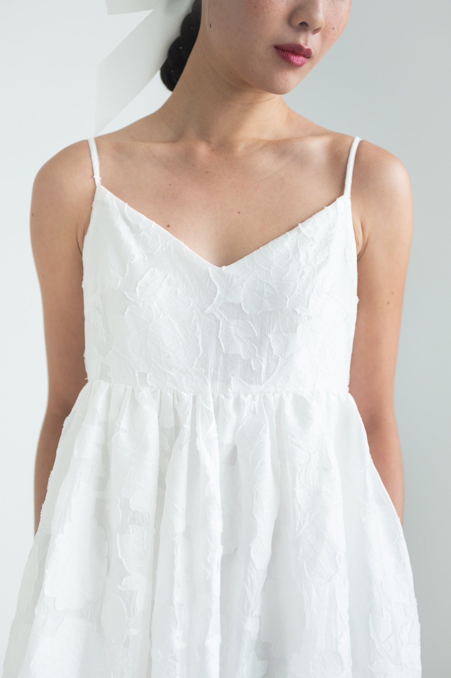 Empire waist dress with a voluminous skirt, adjustable straps, and functional pockets.